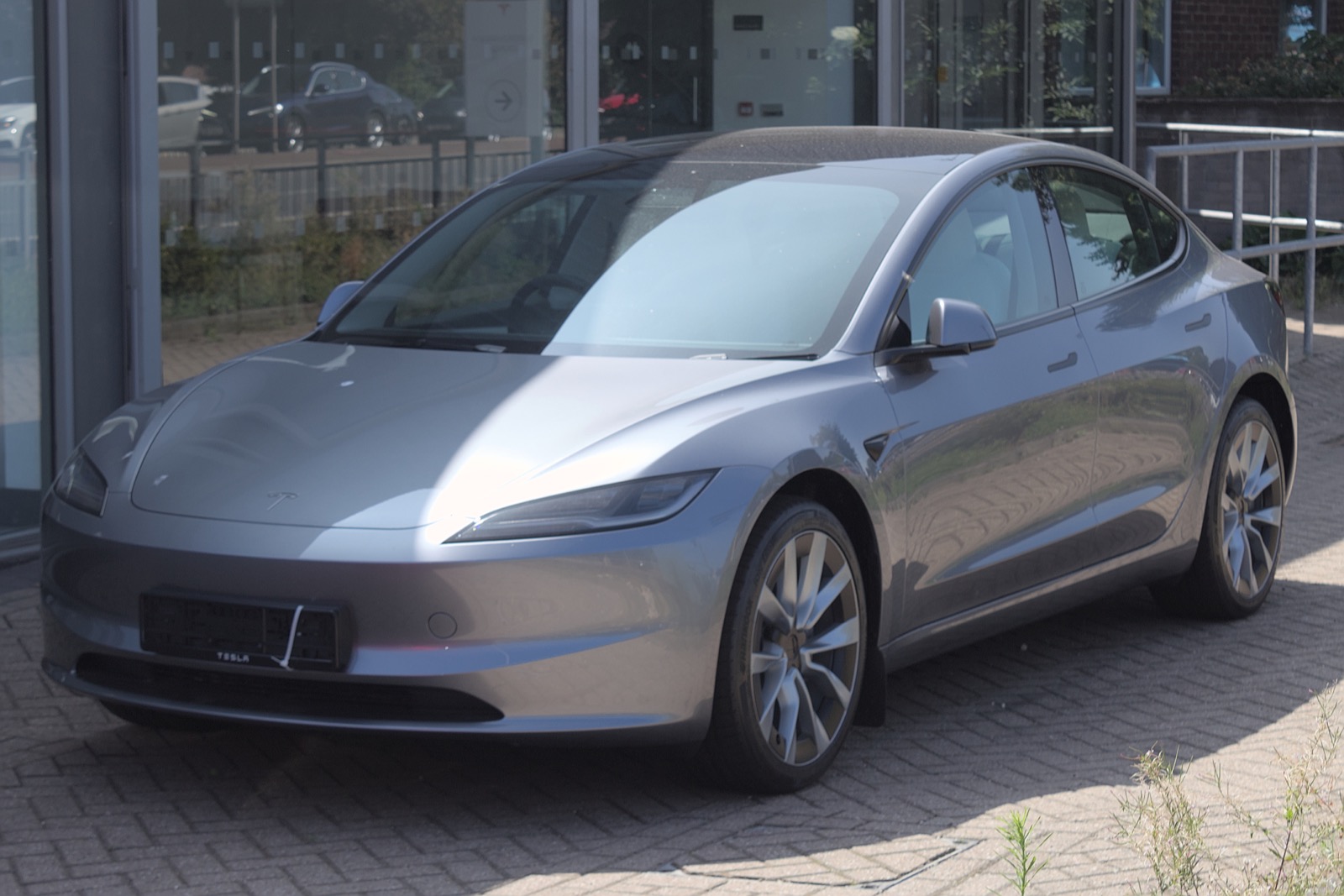 Tesla Model 3 gris estacionado frente a un concesionario